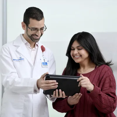 A Young woman looks at a tablet with a physician.