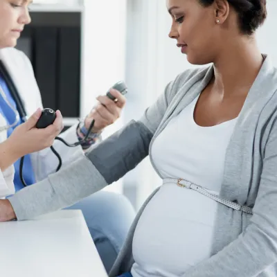 One pregnant woman getting her blood checked by a female doctor in scrubs.