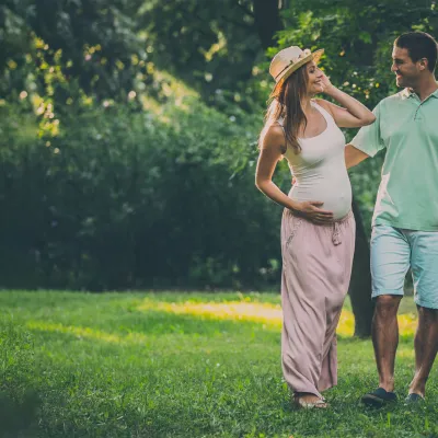 A pregnant woman walking outdoors with her husband.