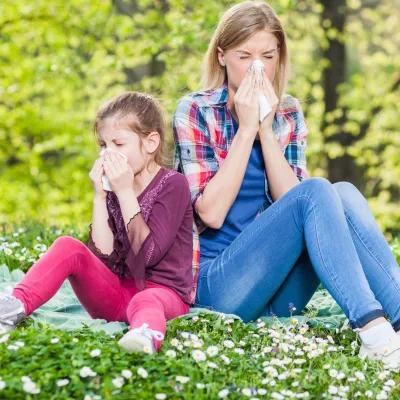 Two ladies experiencing allergy symptoms while sitting outside.
