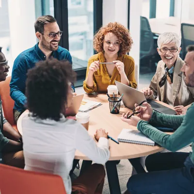 A Group of Co-Workers Sit at a Round Table and Have a Discussion About Work