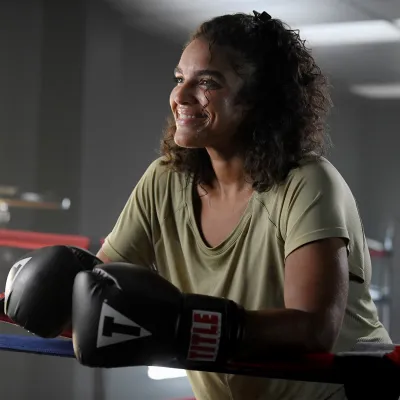 Bariatrics patient Sharlene smiling while wearing boxing gloves and standing in a boxing ring.