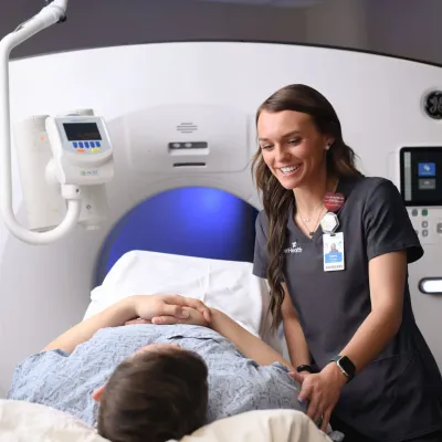 Female imaging technician preparing a male patient for a CT scan.