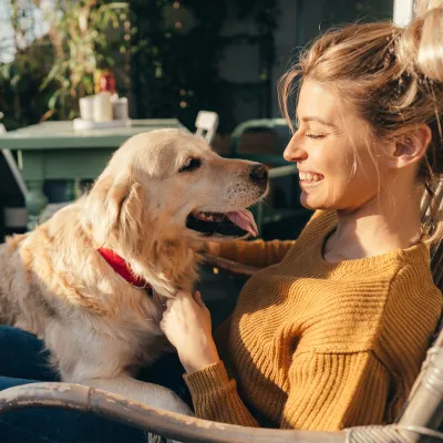 Woman sitting in a chair while on a porch with her dog.