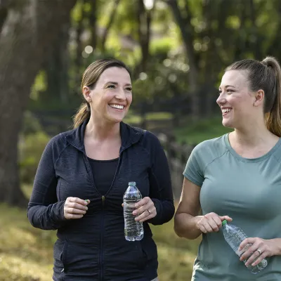 Two women holding water bottles walking together outside 