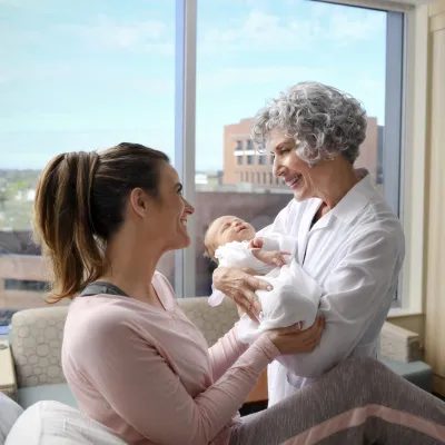 A midwife at an AdventHealth hospital hands a woman her baby.