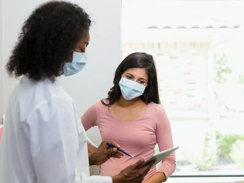 Female doctor goes over a medical chart with a female patient.