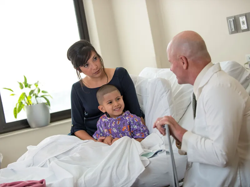 A child patient sits with his mom and smiles at his doctor.