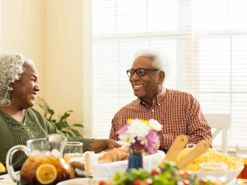 An elderly couple sitting at the table, getting ready to eat lunch.