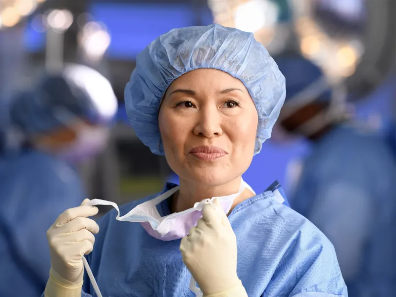 Smiling female surgeon taking off her mask