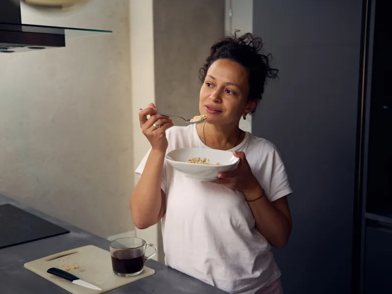 A hispanic woman eating a bowl of food.