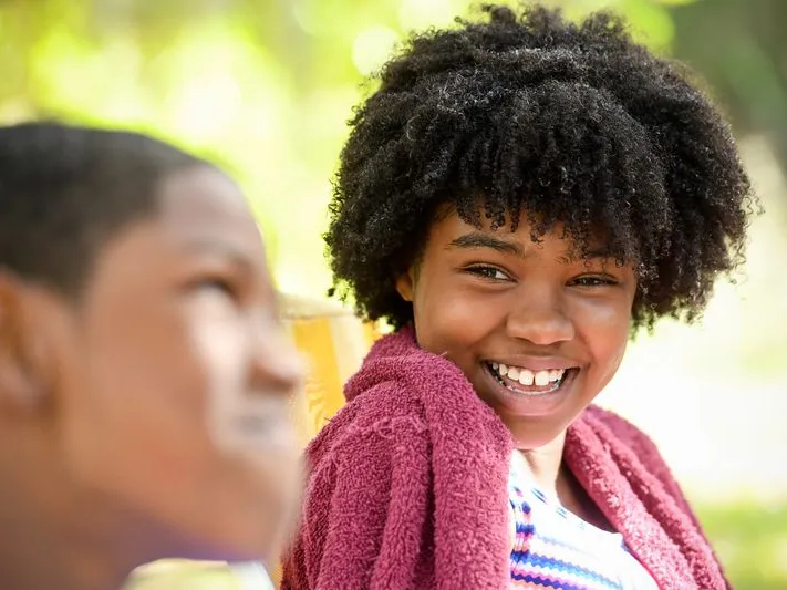 A girl smiles at her older brother