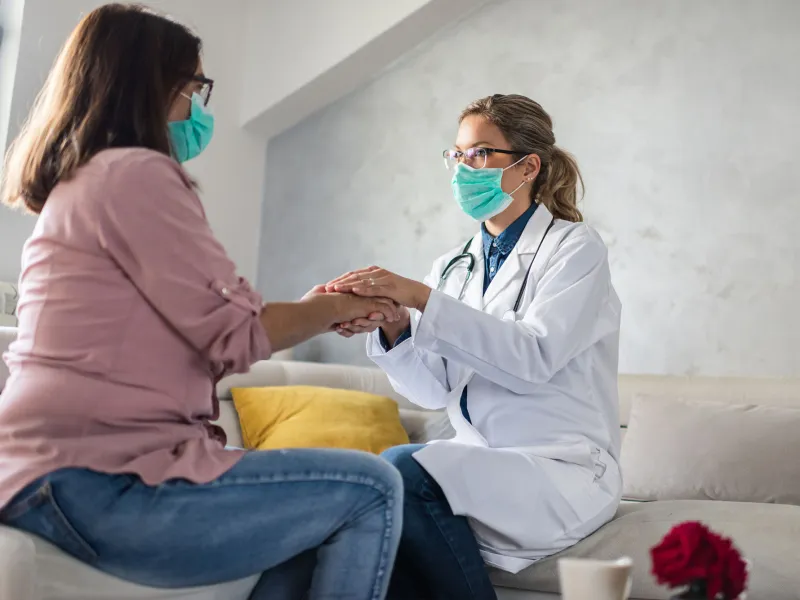 A female physician holding a female patient's hand