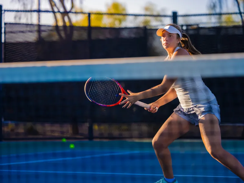 A Woman Playing Tennis Looks Across the Tennis Court as She Prepares to Return a Voley.