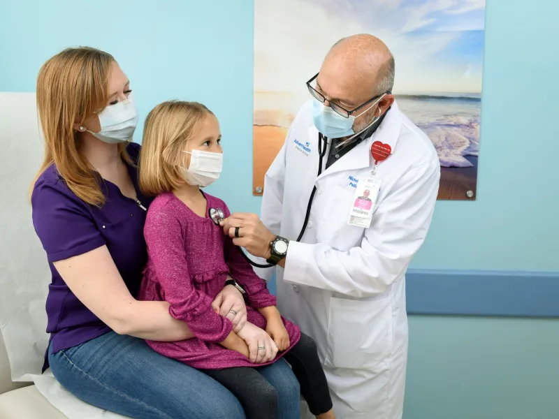 Doctor checking girl's heart beat