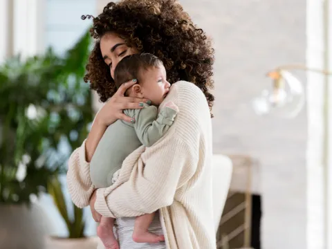 woman holding infant to her shoulder