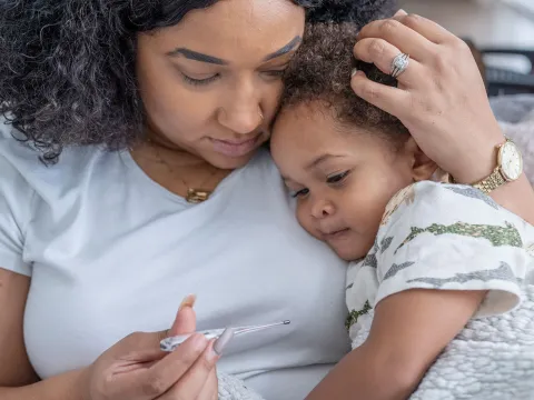 Mom taking temperature of little girl