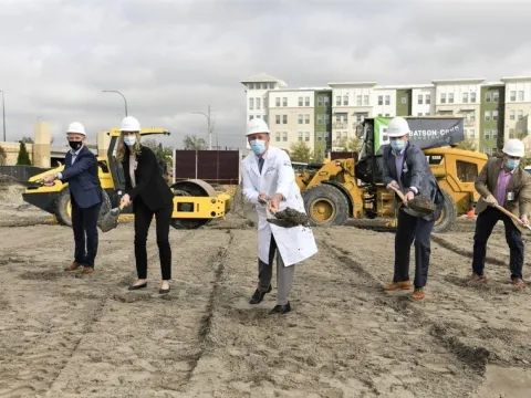 5 executives shovel dirt at Rothman Groundbreaking event