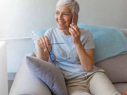 A woman on her cell phone at home on her couch. 