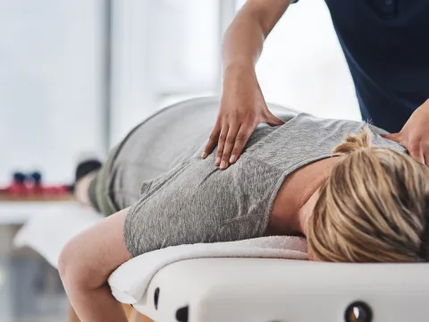Woman laying face down getting her upper back massages by a therapist