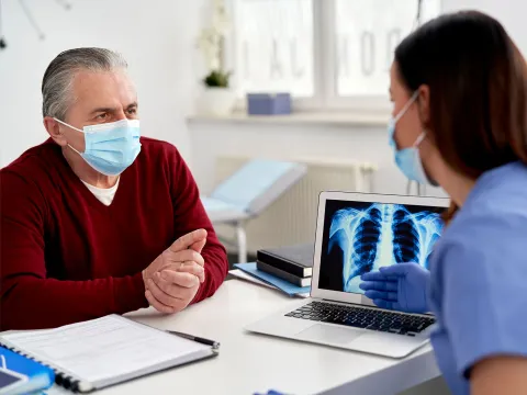 A doctor showing a mature patient his x-ray results on a laptop