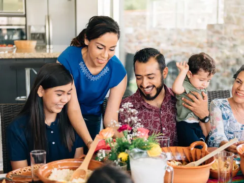 A Hispanic Family Sits Down to a Meal in Their Home.