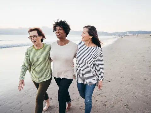 Three ladies walk arm in arm on the beach