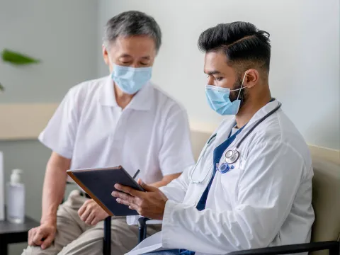 A Doctor Reviews a Patient's Chart with Him on a Tablet in an Exam Room.