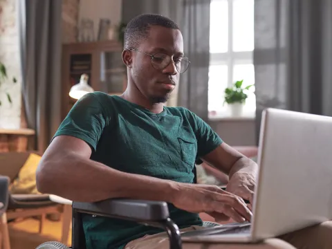 A Black Man Works on His Laptop at Home.