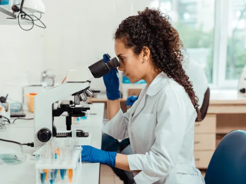 A woman researcher using a microscope.