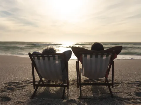 Older couple lounging in beach chairs while on the beach.