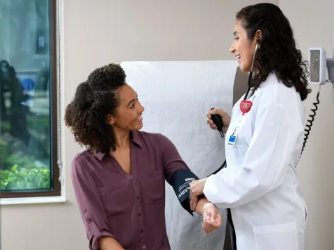 A Doctor Speaks to Her Patient as She Takes Her Vitals in an Exam Room.