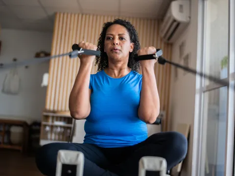 A Woman Exercises with Weight Machine in Her Home