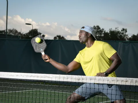 A Man Playing Pickleball on a Tennis Court