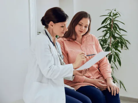 Female Doctor talking to Female Patient Showing Her Paper