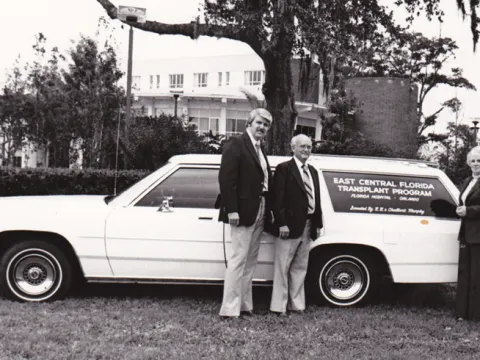 In the 1970s, the first organ procurement automobile was gifted to AdventHealth to help transport kidney donations. Organ procurement coordinators gather around the new vehicle with the generous community members who made the gift. (Dr. Metzger is not pictured.)