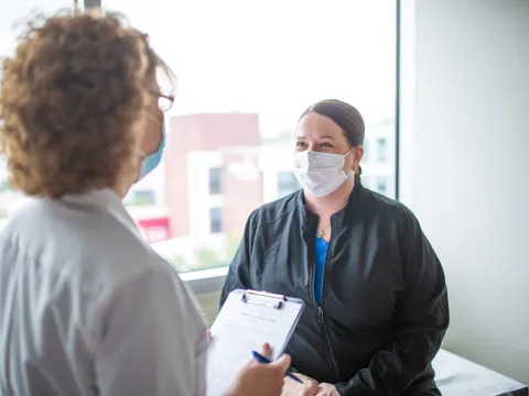 Patient speaking to her doctor, both wearing masks