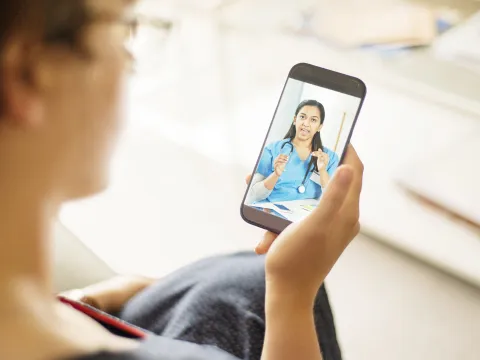 Woman on a Smart Phone having a Virtual Visit with a medical professional.