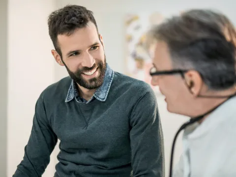 A dark haired and bearded adult man with a male Doctor.