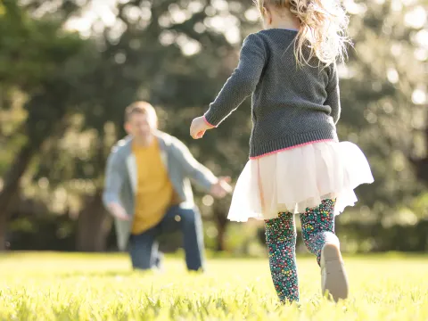A father playing with his little girl in the park.