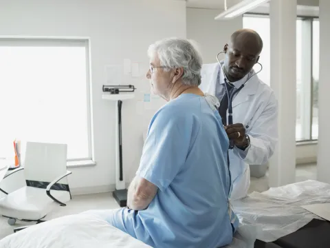 A Caucasian man receives a check-up an African American doctor. 