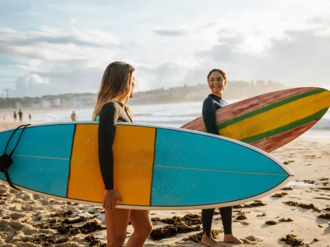 Two healthy women enjoy surfing at the beach.