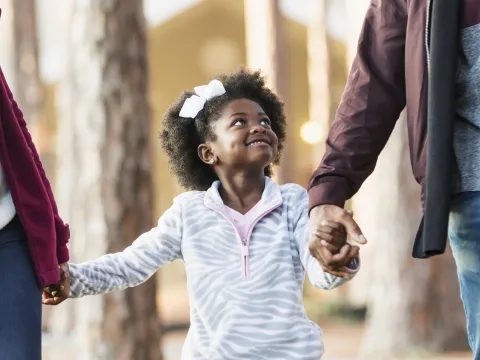 Young girl walks with her parents at the park