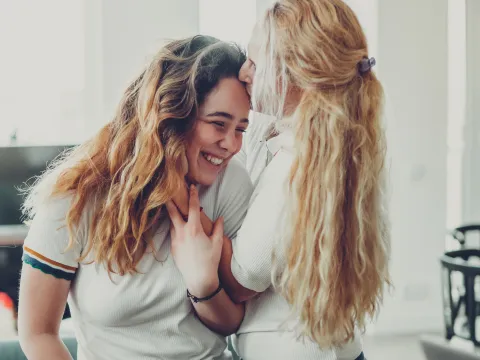 A mother kisses her teenage daughter.