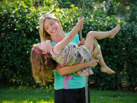 A mom helps her daughter swing.