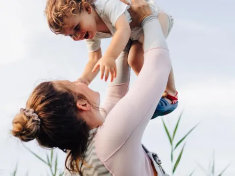 a woman raises up a baby in her arms