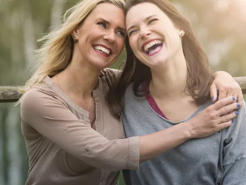 Two sisters hugging and laughing.