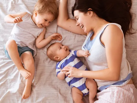 A mom snuggles her two children in bed.