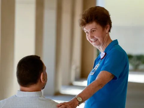 A Senior Woman Volunteer Comforts a Patient Outside.
