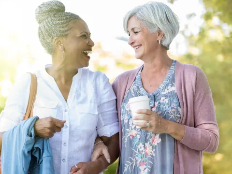 Two healthy mature women enjoy a walk outdoors together.